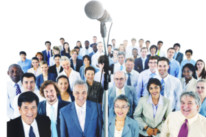 Diverse group of professionals standing behind a large microphone, ready to speak at a conference.